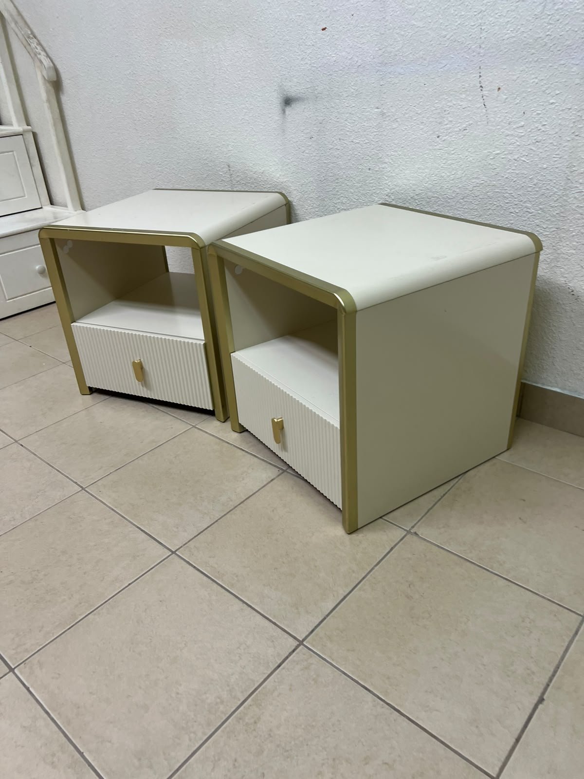 The image shows two modern bedside tables in a creamy white finish, featuring gold frames and details, as well as ribbed drawer fronts (from Home Centre). - Image 4