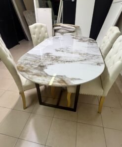 An oval dining table with a marble-patterned ceramic top, surrounded by four chairs upholstered in light beige fabric and featuring button-tufted backrests. - Image 11