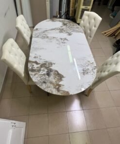 An oval dining table with a marble-patterned ceramic top, surrounded by four chairs upholstered in light beige fabric and featuring button-tufted backrests. - Image 4
