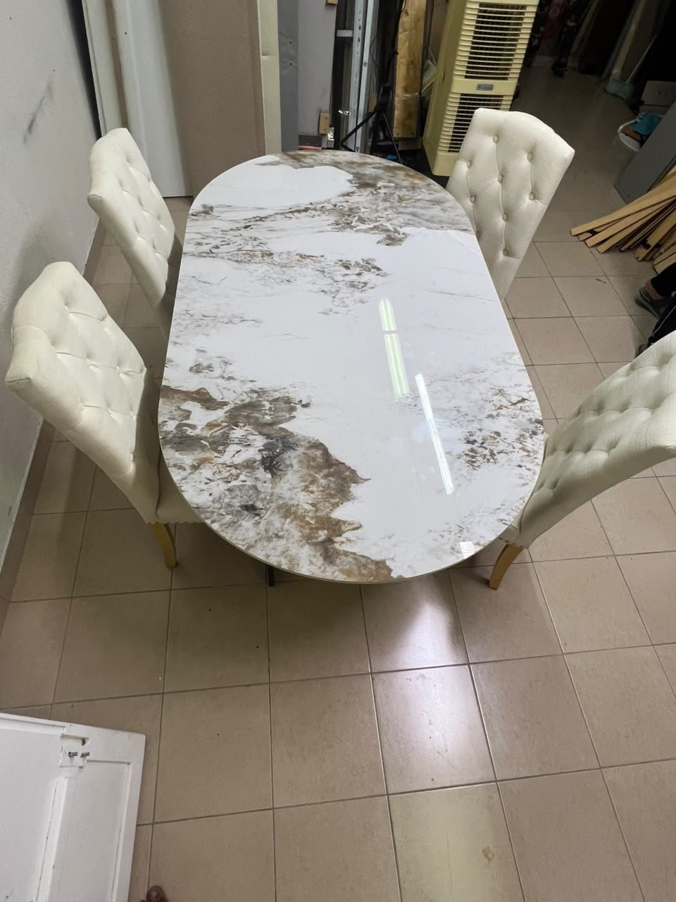 An oval dining table with a marble-patterned ceramic top, surrounded by four chairs upholstered in light beige fabric and featuring button-tufted backrests. - Image 4