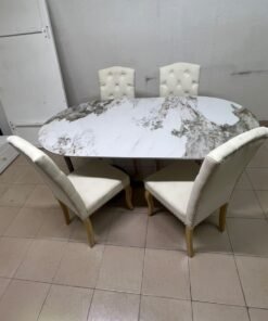 An oval dining table with a marble-patterned ceramic top, surrounded by four chairs upholstered in light beige fabric and featuring button-tufted backrests. - Image 5