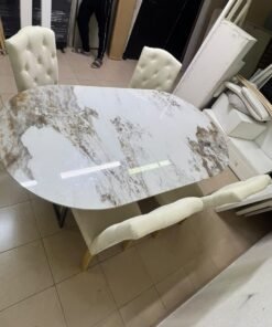 An oval dining table with a marble-patterned ceramic top, surrounded by four chairs upholstered in light beige fabric and featuring button-tufted backrests. - Image 6