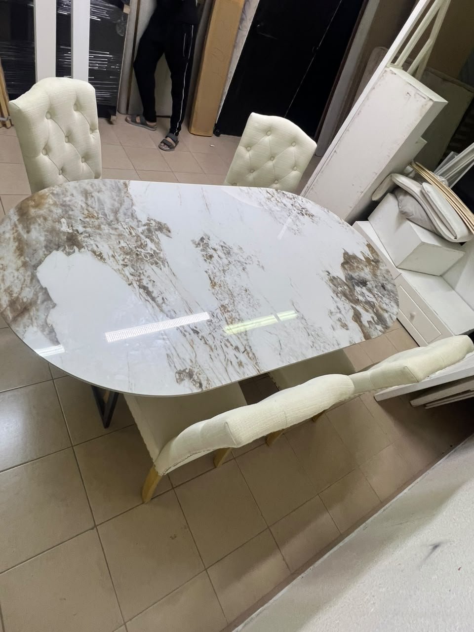 An oval dining table with a marble-patterned ceramic top, surrounded by four chairs upholstered in light beige fabric and featuring button-tufted backrests. - Image 6