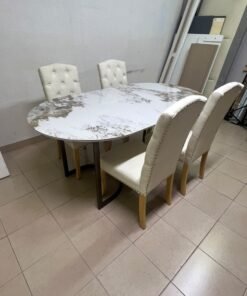 An oval dining table with a marble-patterned ceramic top, surrounded by four chairs upholstered in light beige fabric and featuring button-tufted backrests. - Image 8
