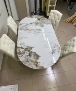 An oval dining table with a marble-patterned ceramic top, surrounded by four chairs upholstered in light beige fabric and featuring button-tufted backrests. - Image 9