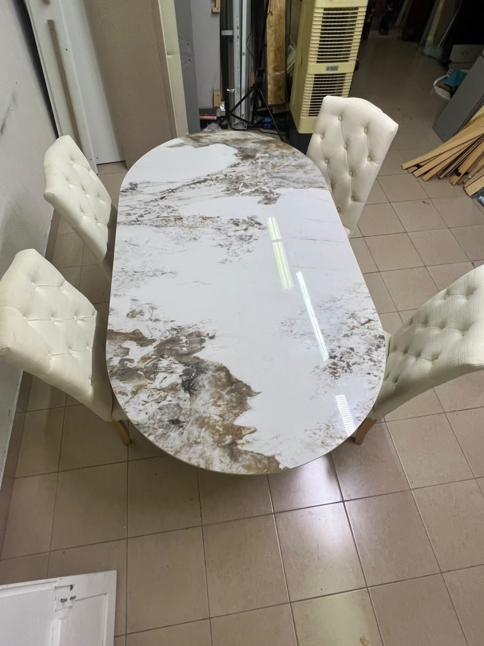 An oval dining table with a marble-patterned ceramic top, surrounded by four chairs upholstered in light beige fabric and featuring button-tufted backrests. - Image 9