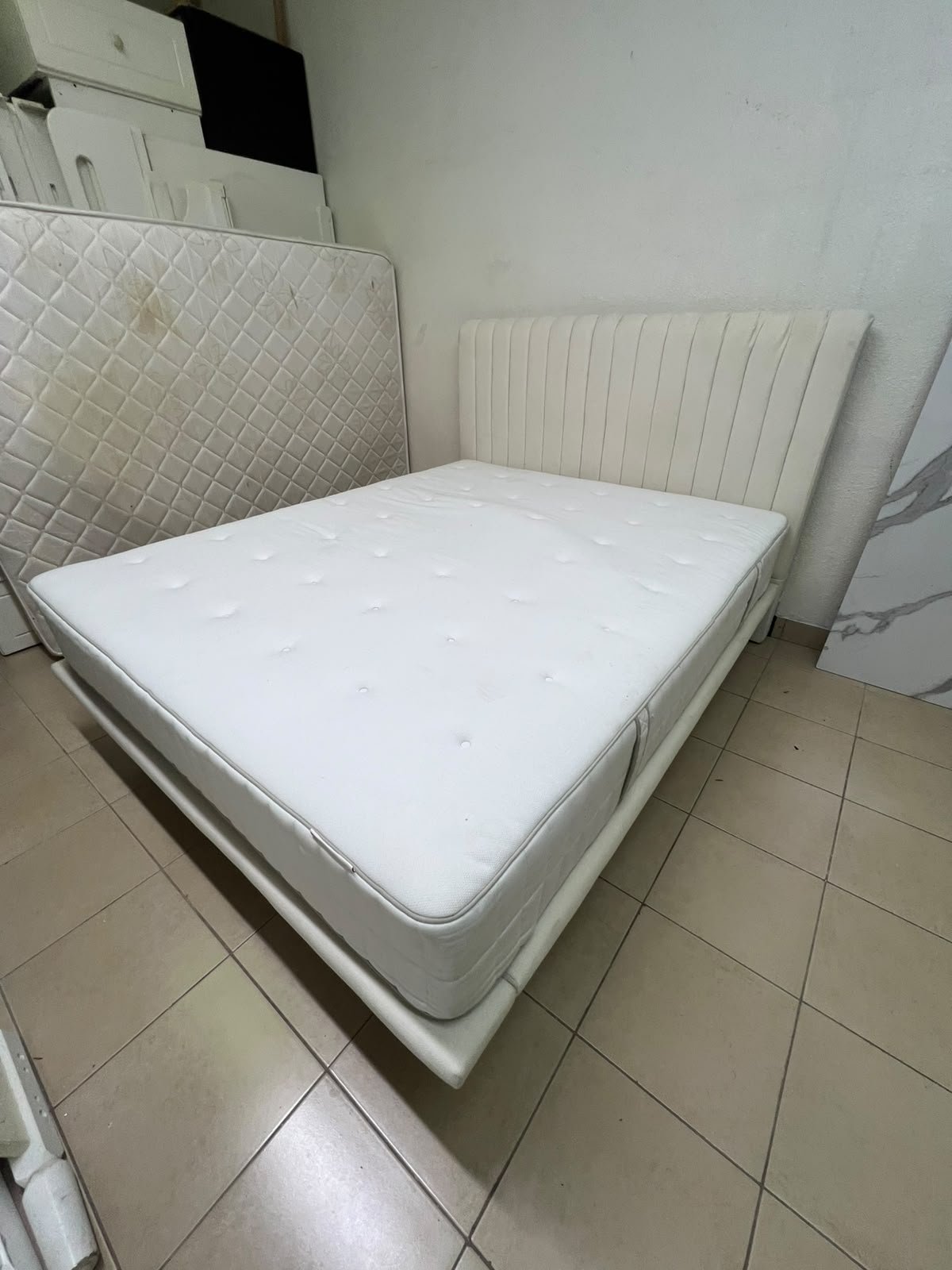 An upholstered double bed in white or light beige with a striped headboard, featuring a comfortable white mattress – Home Centre. - Image 2