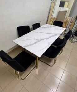 A modern six-seater dining set featuring an elegant design that combines a white marble-patterned tabletop with a gold metal base and frame, paired with black velvet chairs featuring matching gold legs. - Image 2