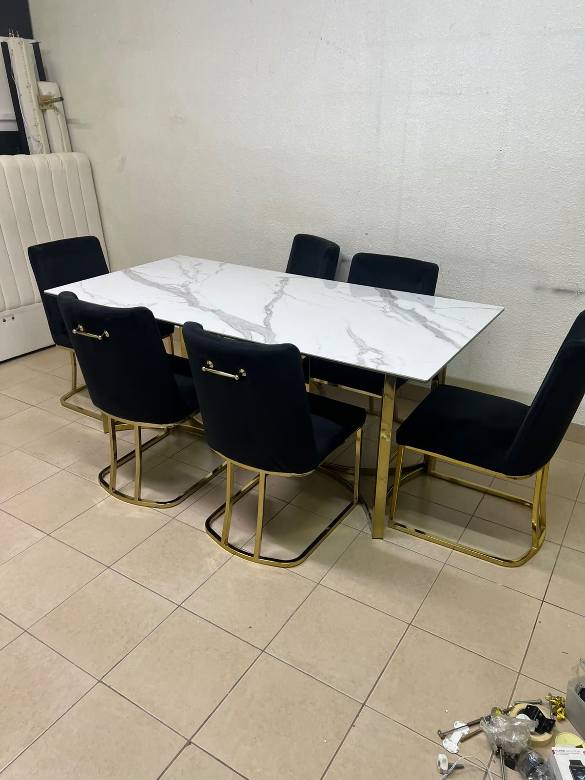 A modern six-seater dining set featuring an elegant design that combines a white marble-patterned tabletop with a gold metal base and frame, paired with black velvet chairs featuring matching gold legs. - Image 4