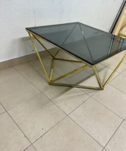 A modern, square coffee table featuring a dark or smoked glass top and a cohesive, diamond-inspired geometric base made of metal or polished gold-tone steel. - Image 2