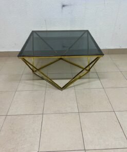 A modern, square coffee table featuring a dark or smoked glass top and a cohesive, diamond-inspired geometric base made of metal or polished gold-tone steel. - Image 3