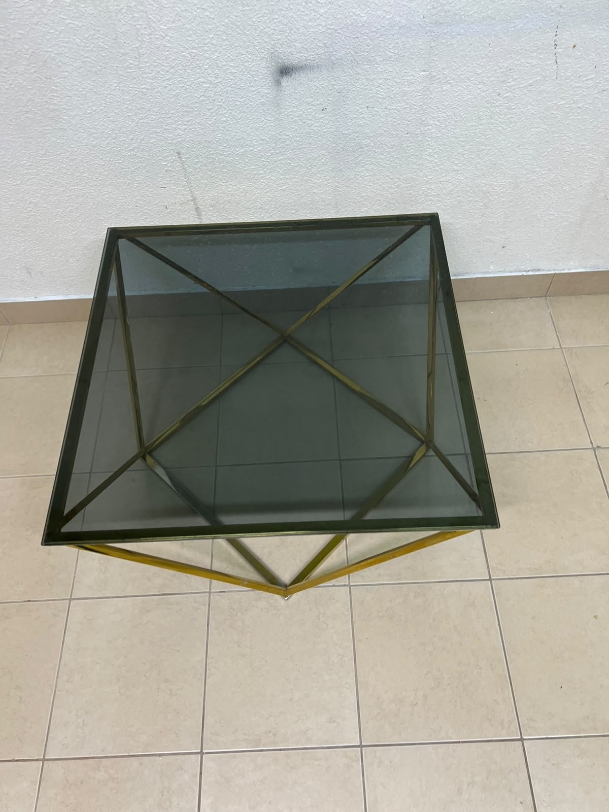 A modern, square coffee table featuring a dark or smoked glass top and a cohesive, diamond-inspired geometric base made of metal or polished gold-tone steel. - Image 5