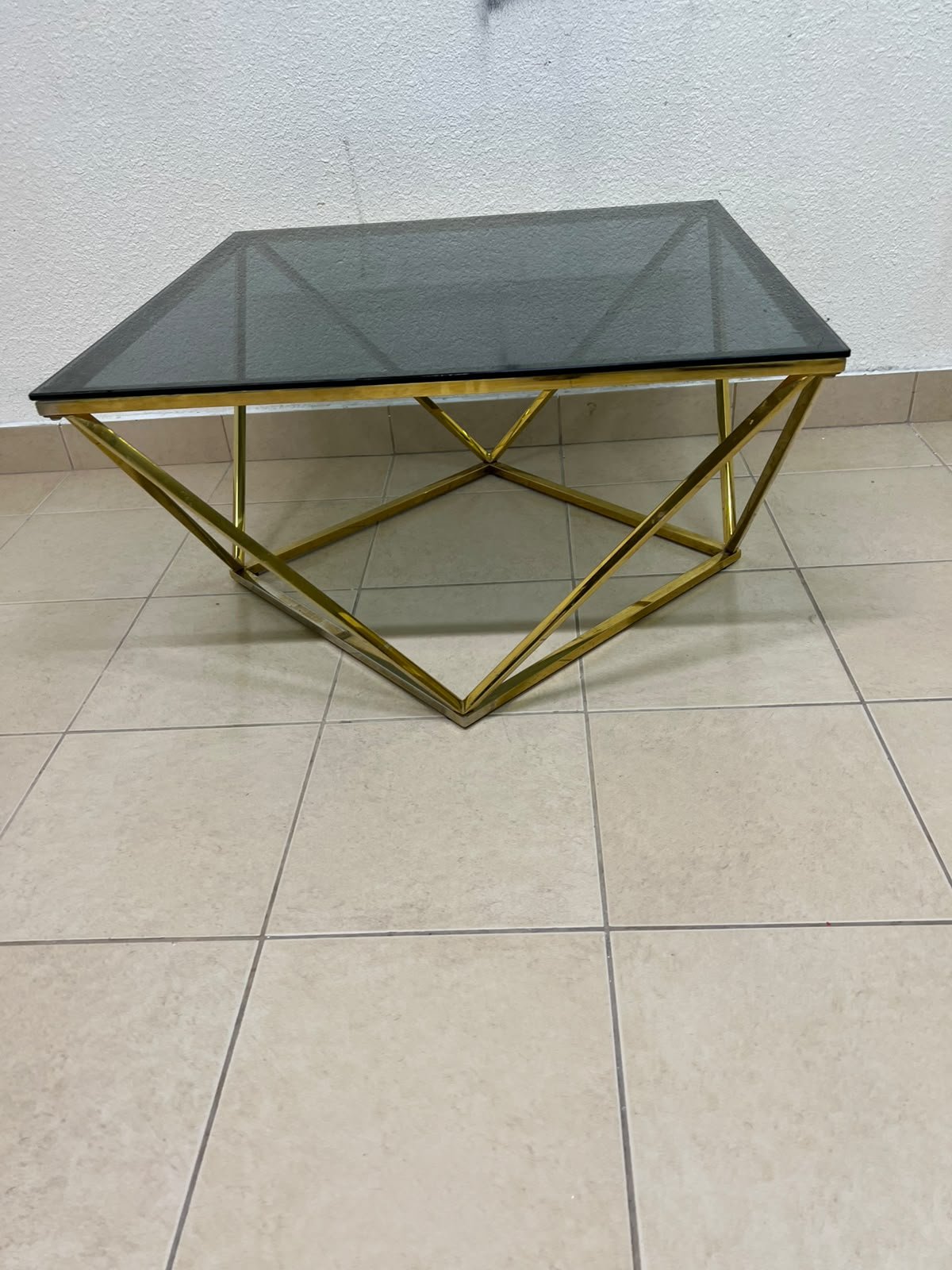 A modern, square coffee table featuring a dark or smoked glass top and a cohesive, diamond-inspired geometric base made of metal or polished gold-tone steel. - Image 7