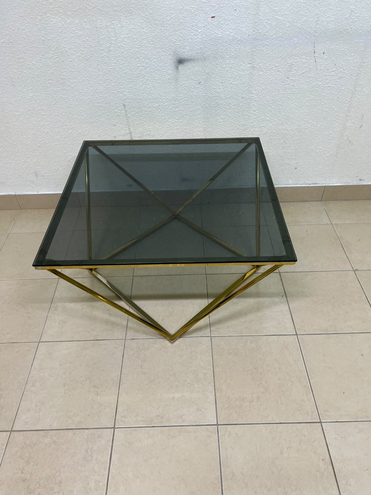 A modern, square coffee table featuring a dark or smoked glass top and a cohesive, diamond-inspired geometric base made of metal or polished gold-tone steel. - Image 9