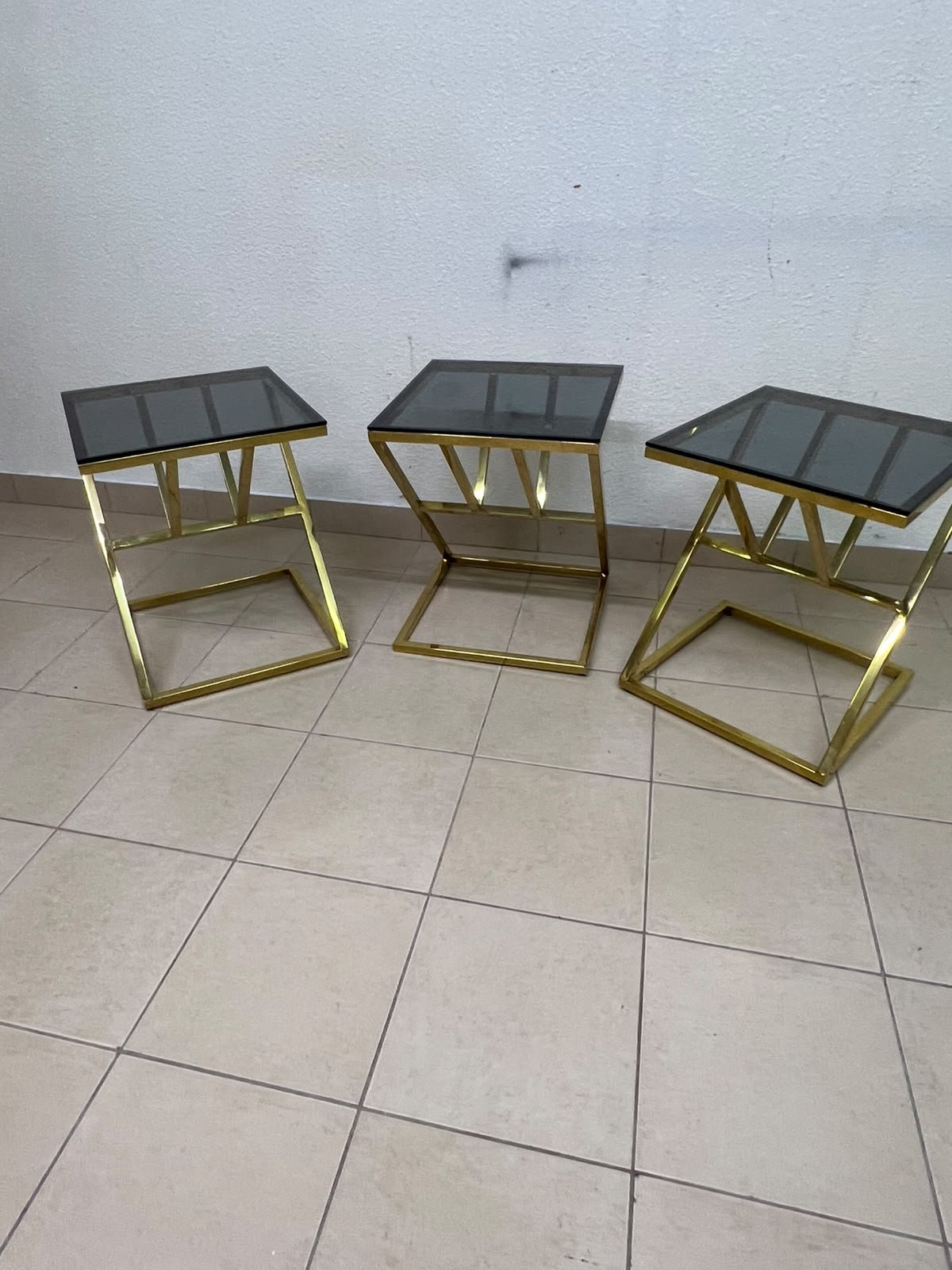 "Zicon" side table set featuring a contemporary geometric Z-shaped design, with gold-finished stainless steel or metal bases and dark or reflective glass tops. - Image 2