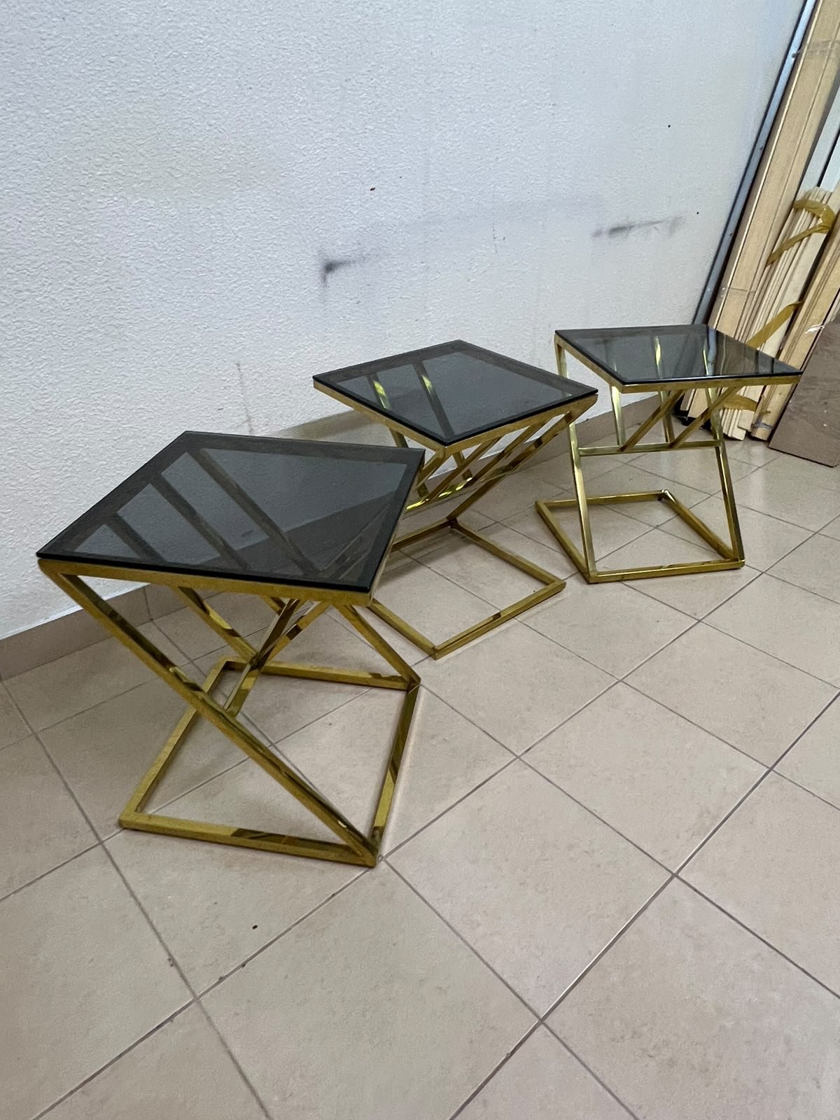 "Zicon" side table set featuring a contemporary geometric Z-shaped design, with gold-finished stainless steel or metal bases and dark or reflective glass tops.