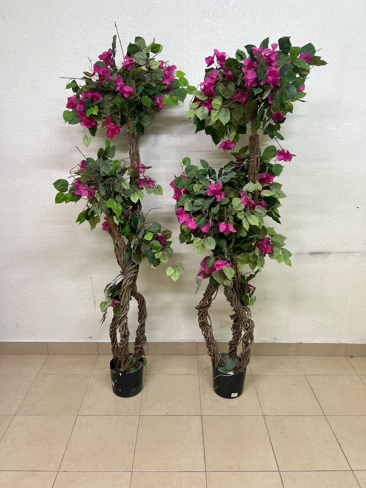 An artificial Bougainvillea tree featuring attractive pink blossoms and green foliage, distinguished by natural, expertly braided wooden trunks and set in black plastic pots. - Image 4