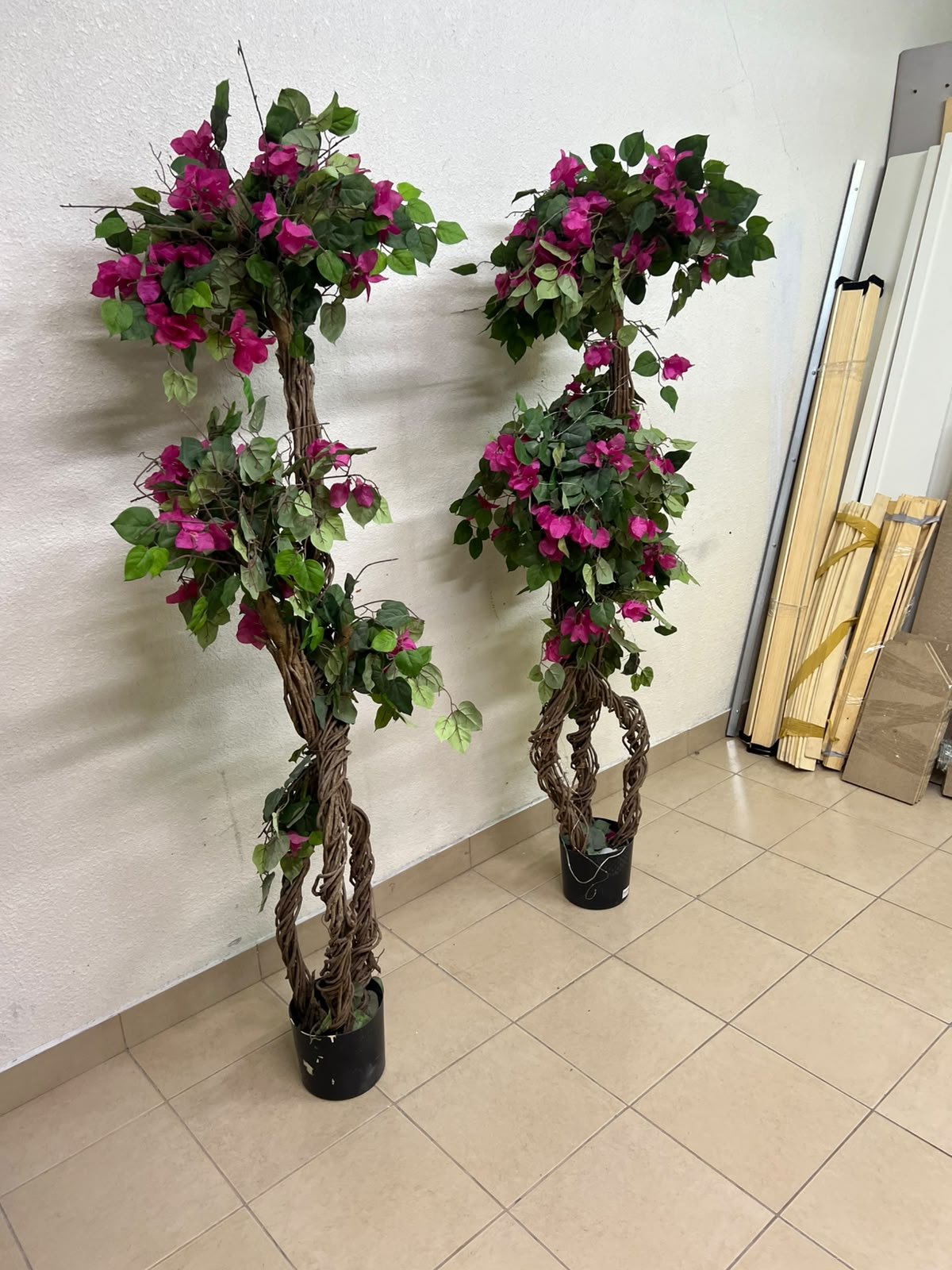 An artificial Bougainvillea tree featuring attractive pink blossoms and green foliage, distinguished by natural, expertly braided wooden trunks and set in black plastic pots. - Image 5