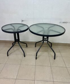 A round garden table featuring a black metal frame and a tempered glass top, suitable for outdoor use on balconies or in gardens.
