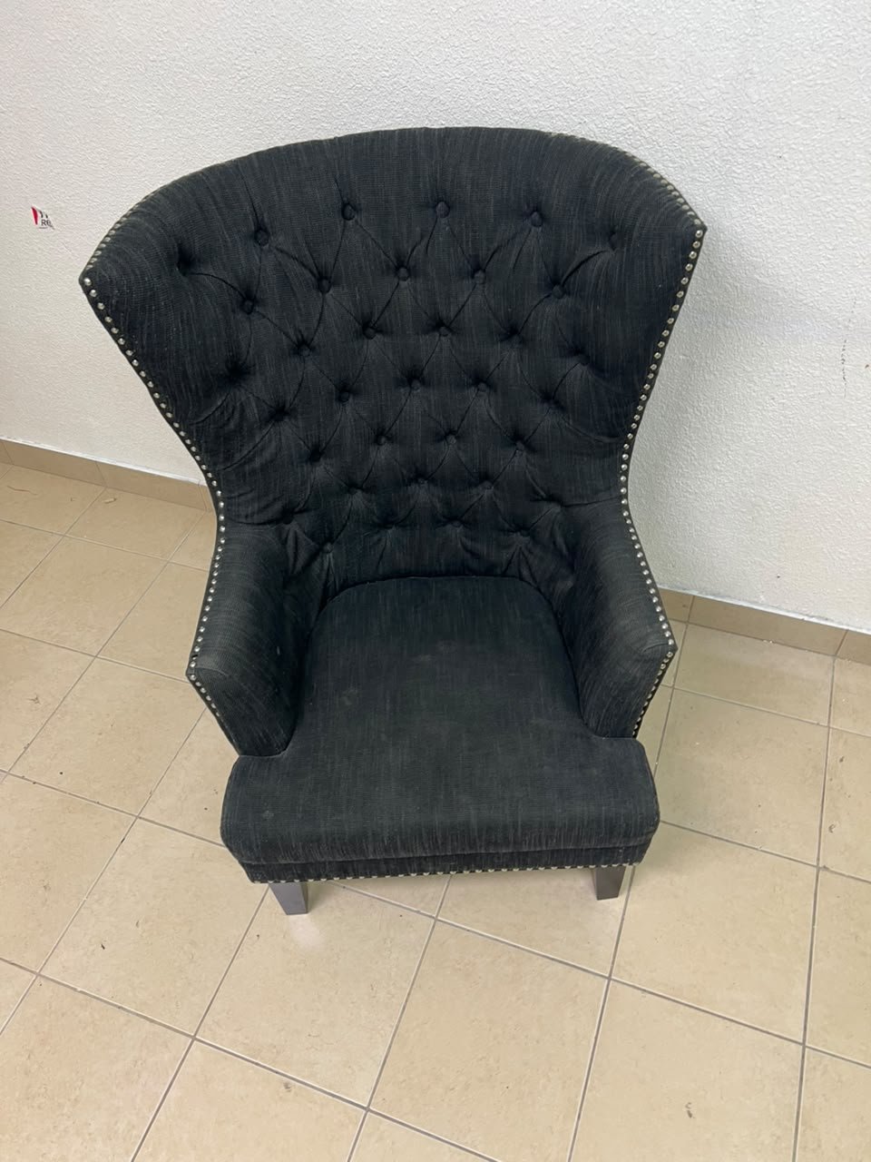 A single upholstered wingback chair featuring a button-tufted back, a black or dark gray fabric finish, and metal nailhead trim along the edges. - Image 3