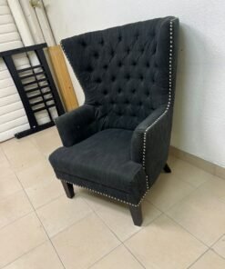 A single upholstered wingback chair featuring a button-tufted back, a black or dark gray fabric finish, and metal nailhead trim along the edges. - Image 4