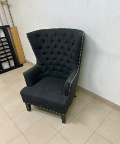 A single upholstered wingback chair featuring a button-tufted back, a black or dark gray fabric finish, and metal nailhead trim along the edges. - Image 6