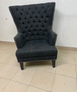 A single upholstered wingback chair featuring a button-tufted back, a black or dark gray fabric finish, and metal nailhead trim along the edges. - Image 11