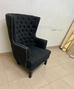 A single upholstered wingback chair featuring a button-tufted back, a black or dark gray fabric finish, and metal nailhead trim along the edges. - Image 10