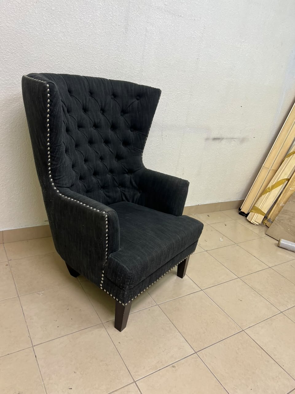A single upholstered wingback chair featuring a button-tufted back, a black or dark gray fabric finish, and metal nailhead trim along the edges. - Image 10