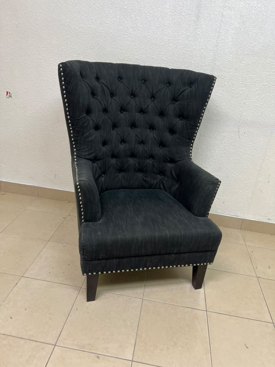 A single upholstered wingback chair featuring a button-tufted back, a black or dark gray fabric finish, and metal nailhead trim along the edges. - Image 9