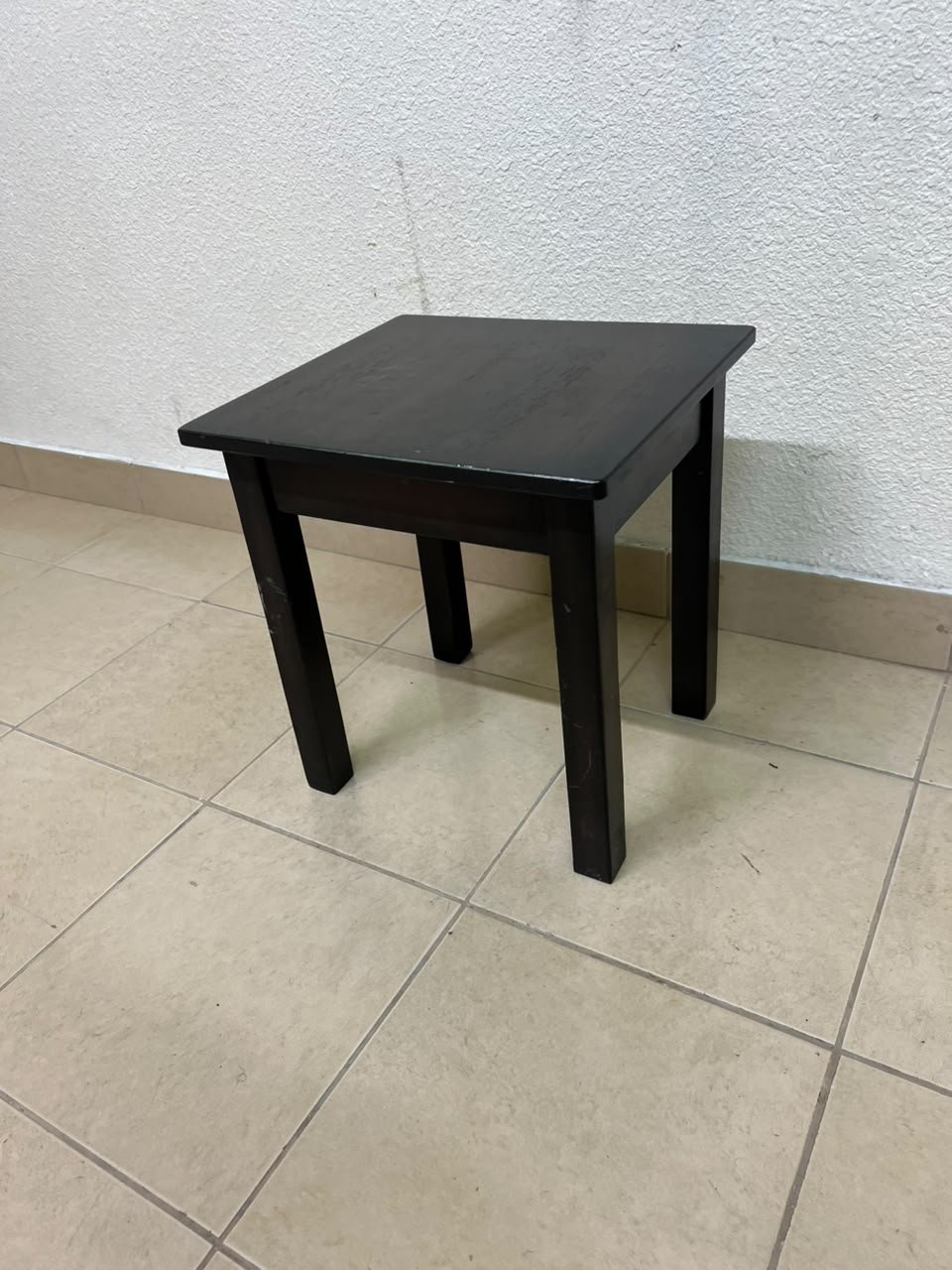 A small, square wooden side table with a dark brown or black finish, featuring four straight legs.