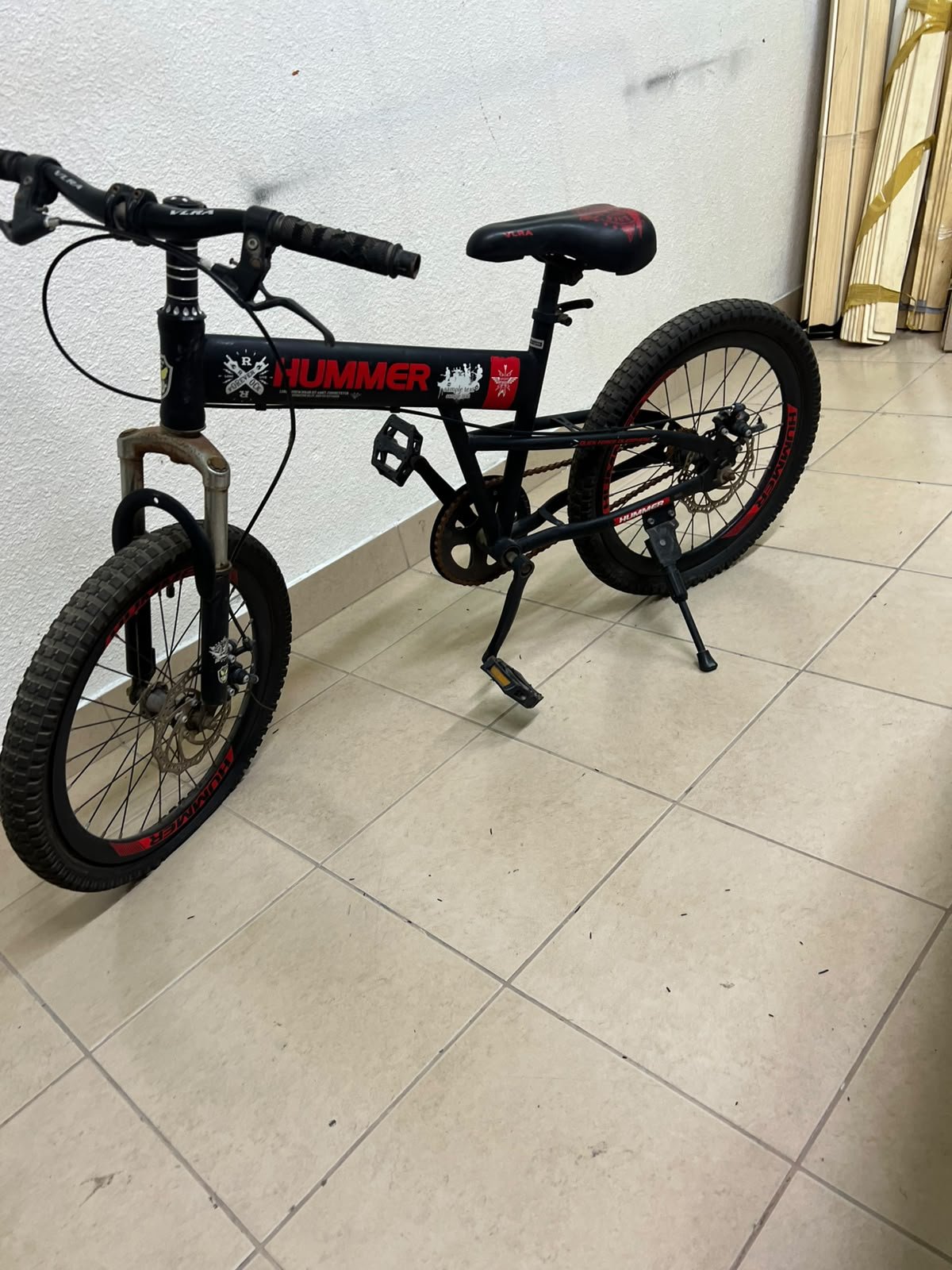 A 20-inch "Hummer"-branded mountain bike featuring a black and red color scheme; it appears to be equipped with a carbon steel or alloy frame, a front suspension system, and dual disc brakes.