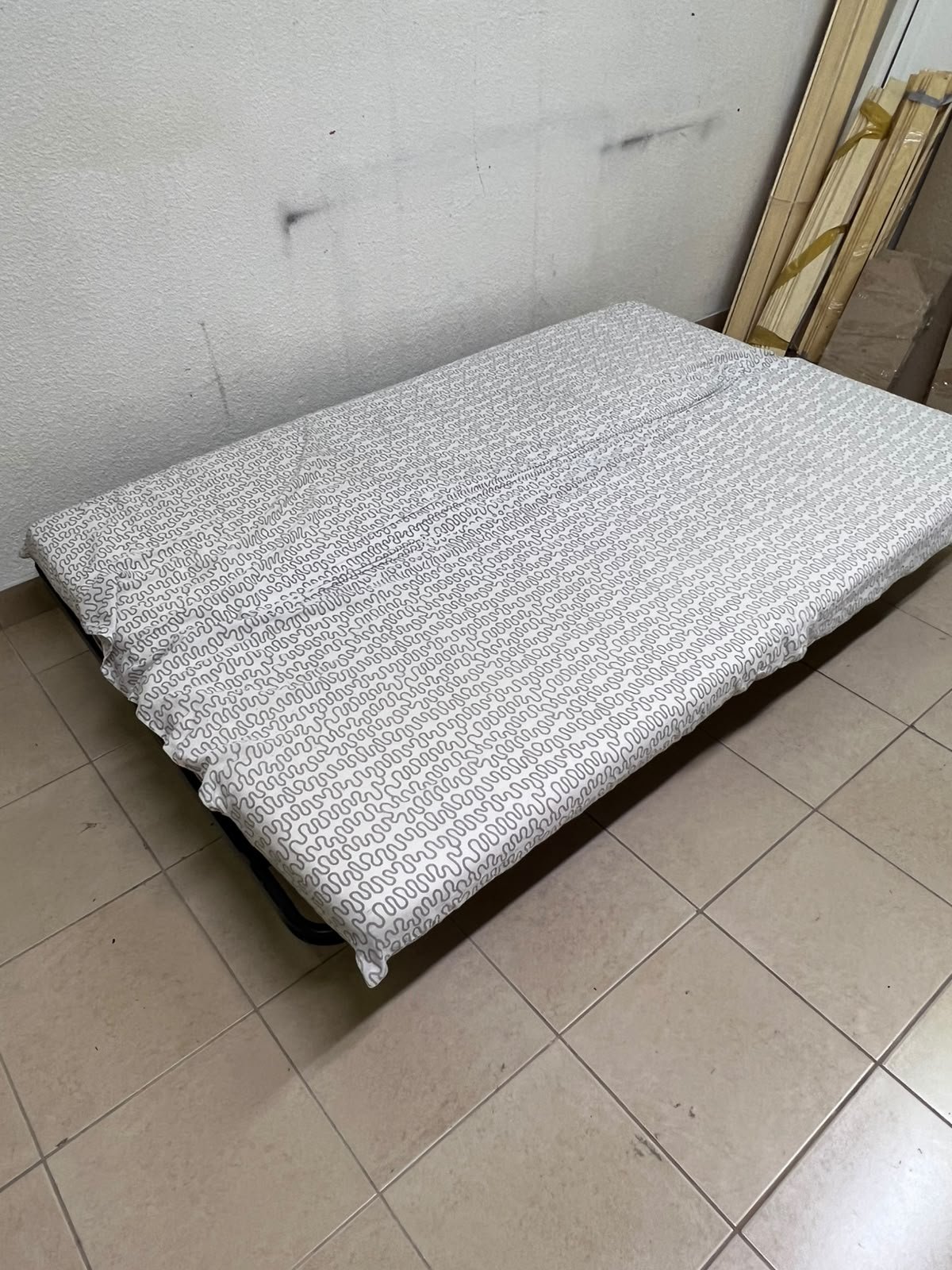 A foldable metal sofa bed (converting into a bed)—the famous IKEA NYHAMN model—featuring a grey-and-white patterned fabric cover and a black frame. - Image 2