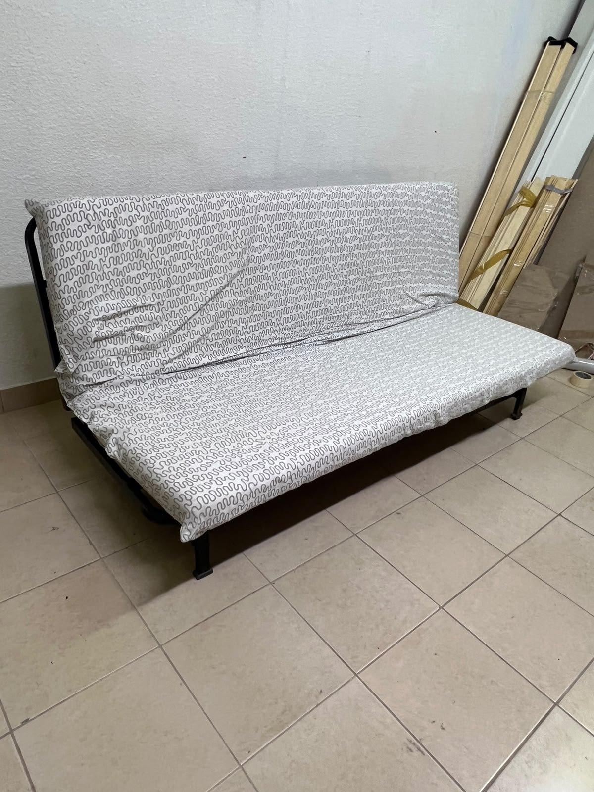 A foldable metal sofa bed (converting into a bed)—the famous IKEA NYHAMN model—featuring a grey-and-white patterned fabric cover and a black frame. - Image 3