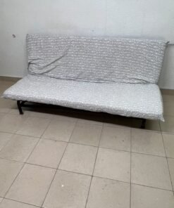 A foldable metal sofa bed (converting into a bed)—the famous IKEA NYHAMN model—featuring a grey-and-white patterned fabric cover and a black frame.