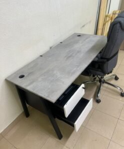 A modern office desk featuring a wooden top with a grey cement-effect finish and black metal legs, accompanied by a suspended side drawer unit in black and white, and a high-back swivel office chair upholstered in grey fabric. - Image 9