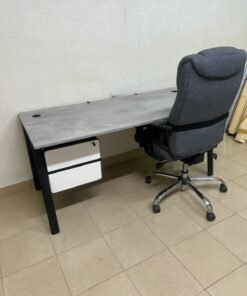A modern office desk featuring a wooden top with a grey cement-effect finish and black metal legs, accompanied by a suspended side drawer unit in black and white, and a high-back swivel office chair upholstered in grey fabric. - Image 6