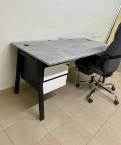 A modern office desk featuring a wooden top with a grey cement-effect finish and black metal legs, accompanied by a suspended side drawer unit in black and white, and a high-back swivel office chair upholstered in grey fabric. - Image 4