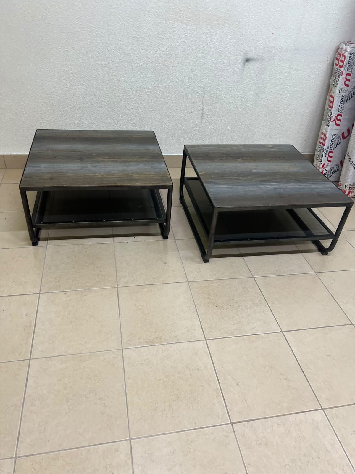 A set of two coffee tables featuring a modern industrial design; each boasts a wooden tabletop with a rustic or distressed look, a sturdy black metal frame and base, and a practical bottom shelf. - Image 7