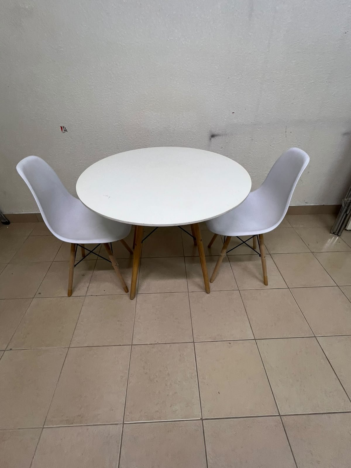 A modern Scandinavian-style round white dining table with wooden legs, accompanied by two matching white chairs. - Image 2