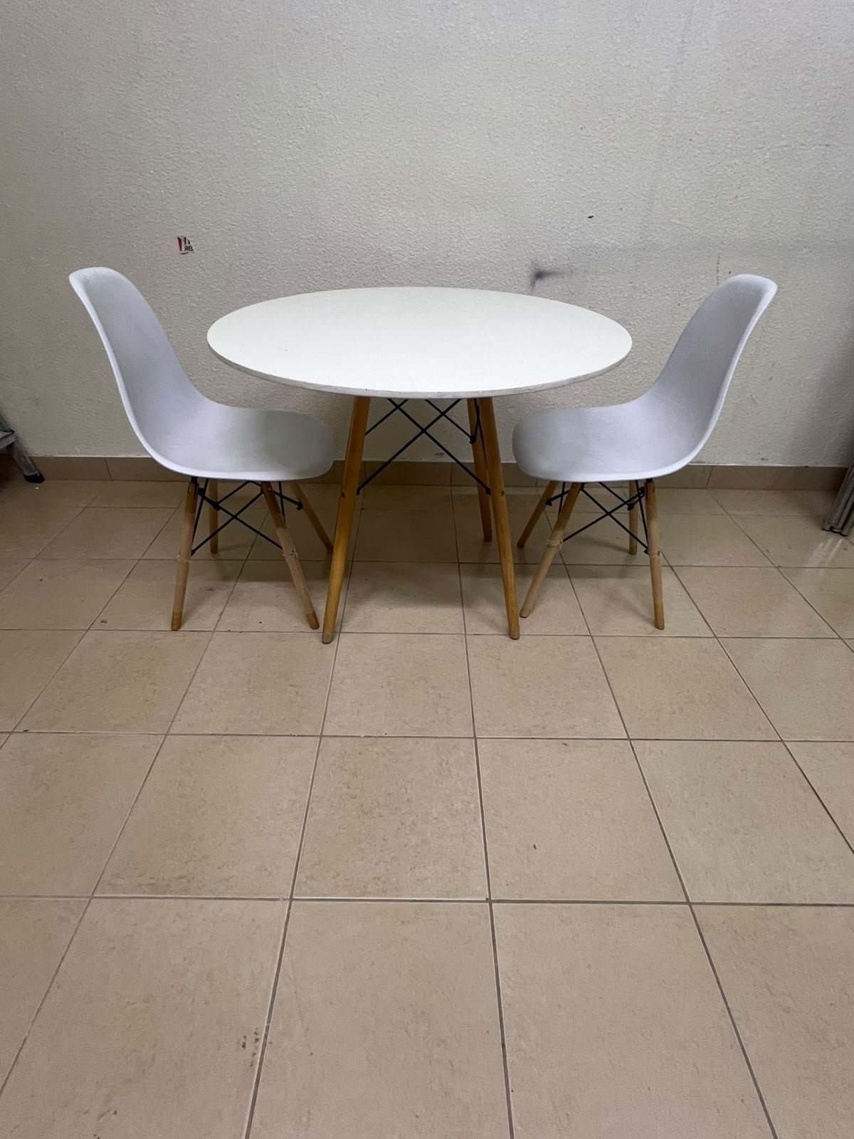 A modern Scandinavian-style round white dining table with wooden legs, accompanied by two matching white chairs. - Image 9
