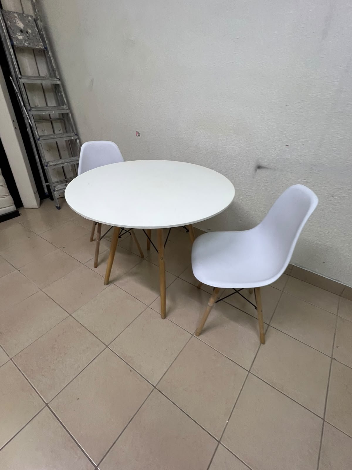 A modern Scandinavian-style round white dining table with wooden legs, accompanied by two matching white chairs. - Image 6