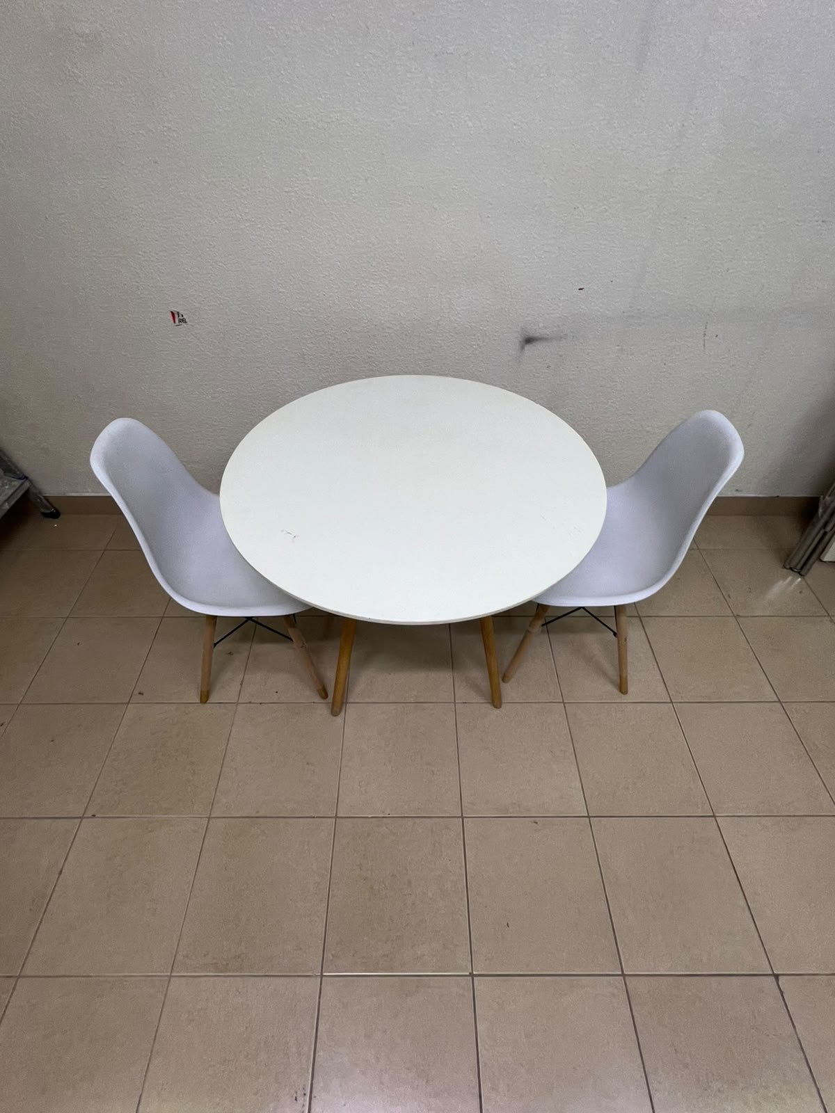 A modern Scandinavian-style round white dining table with wooden legs, accompanied by two matching white chairs. - Image 11