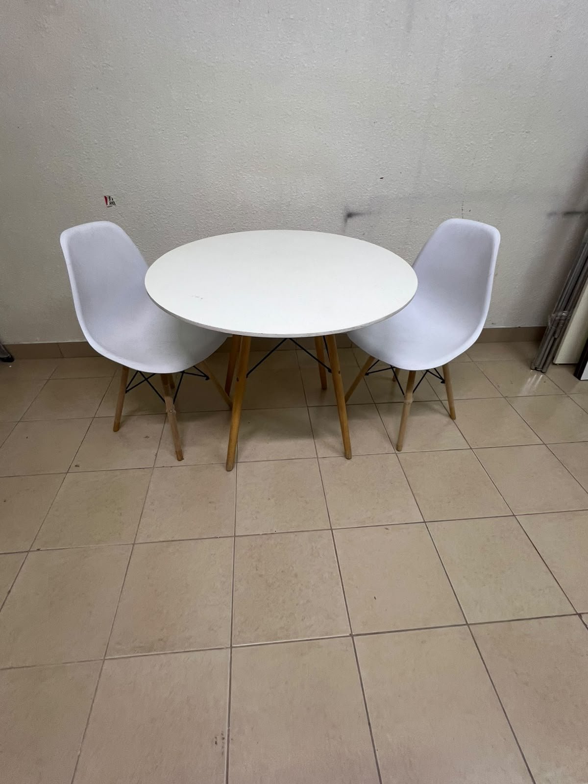 A modern Scandinavian-style round white dining table with wooden legs, accompanied by two matching white chairs. - Image 12
