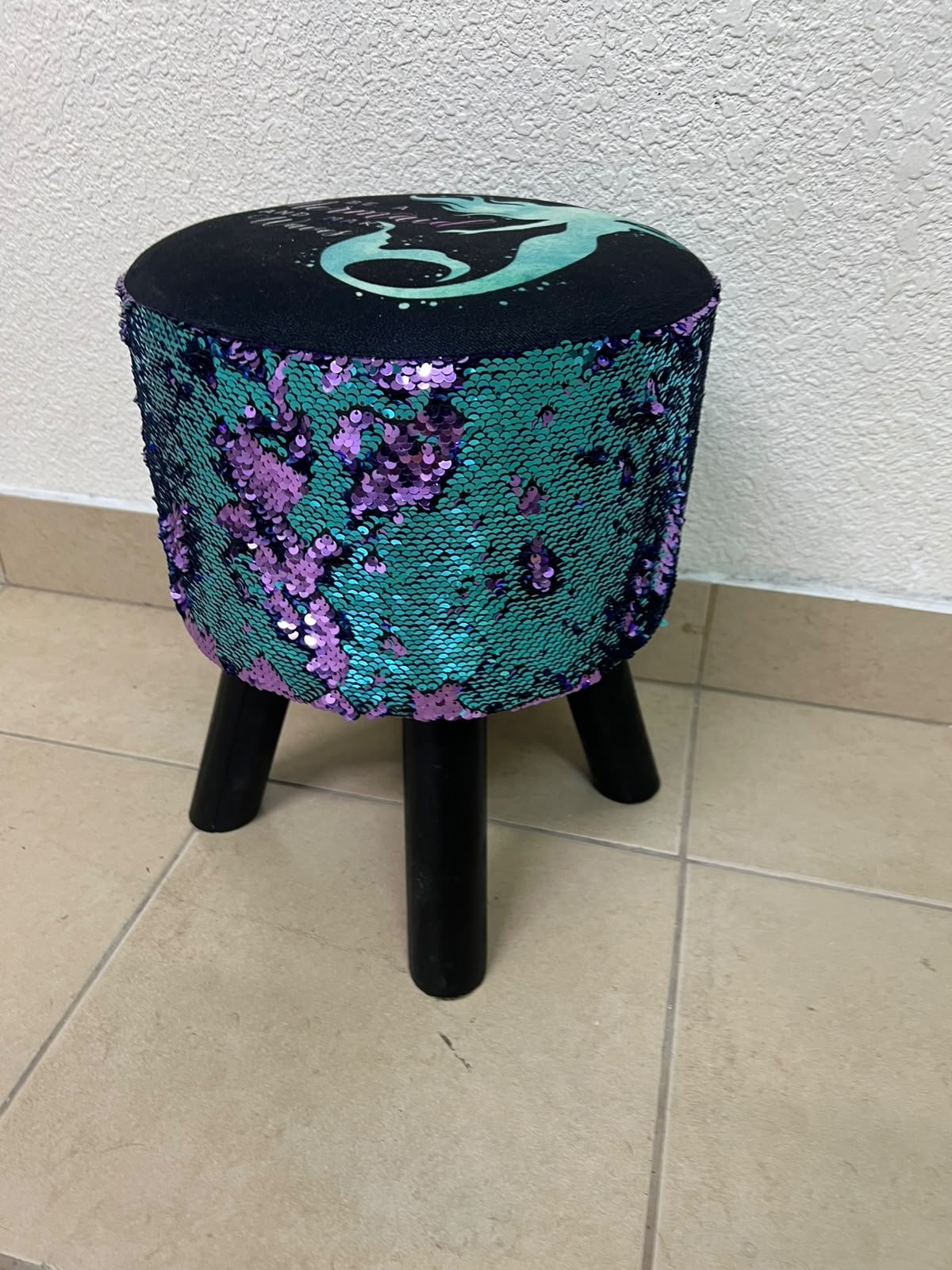 This product is a small decorative stool featuring a "mermaid" sequin design—with reversible sequins that change color—and sturdy black wooden legs.
