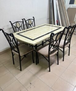 A dining table featuring a metal design with a decorative top and a set of matching upholstered chairs; it appears suitable for home use or a functional office setting.