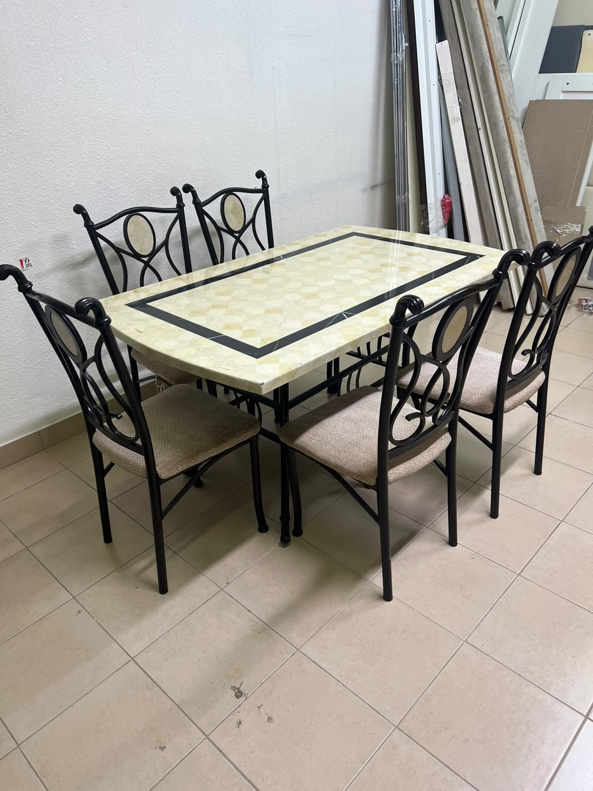 A dining table featuring a metal design with a decorative top and a set of matching upholstered chairs; it appears suitable for home use or a functional office setting.