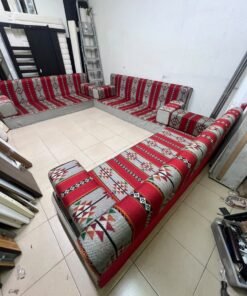 A traditional U-shaped floor seating set (Arabic *majlis*), upholstered in fabric featuring red, heritage-inspired Sadu patterns.