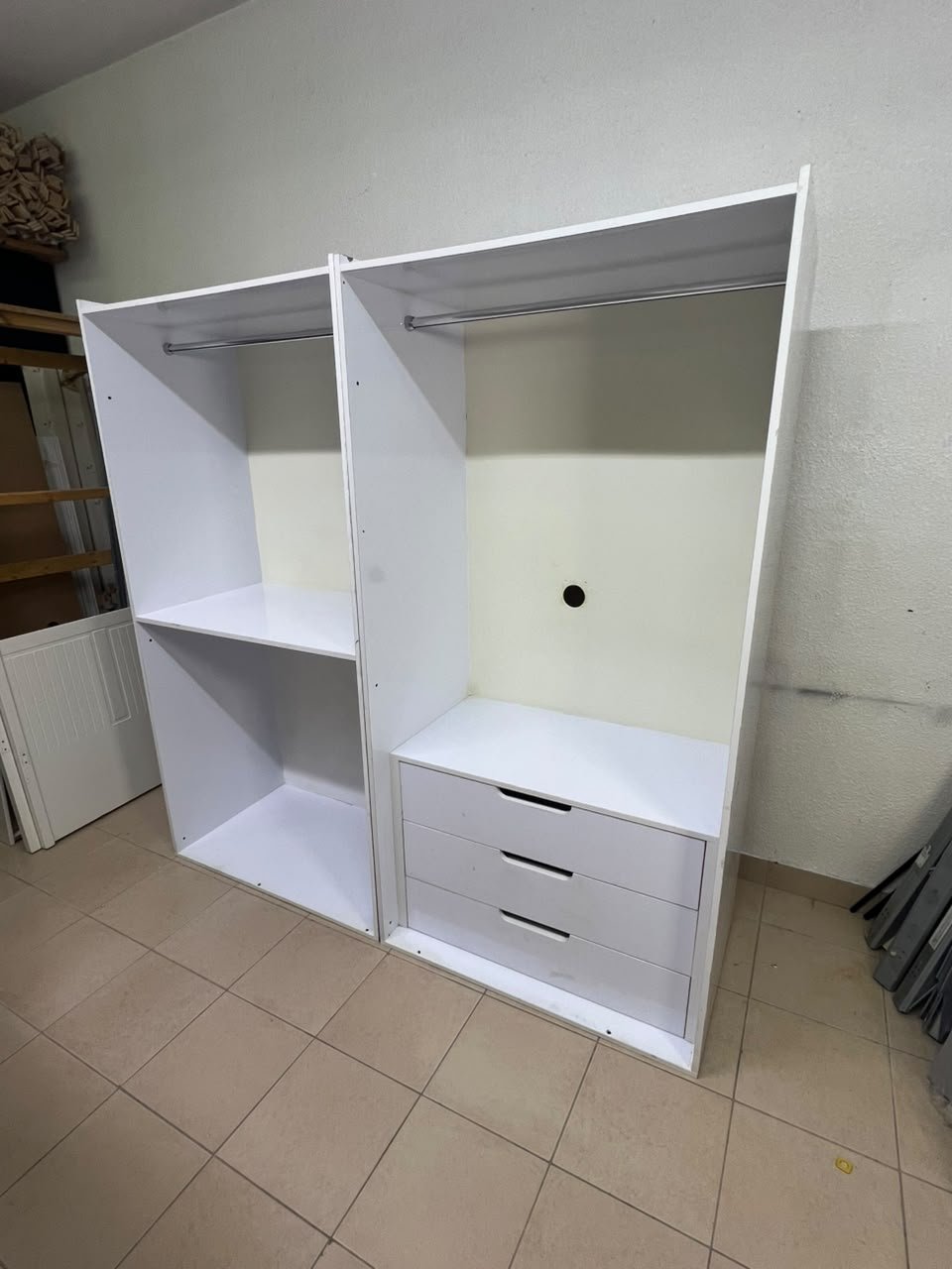 A white open wardrobe unit made of MDF, featuring shelves, drawers, and a clothes rail.