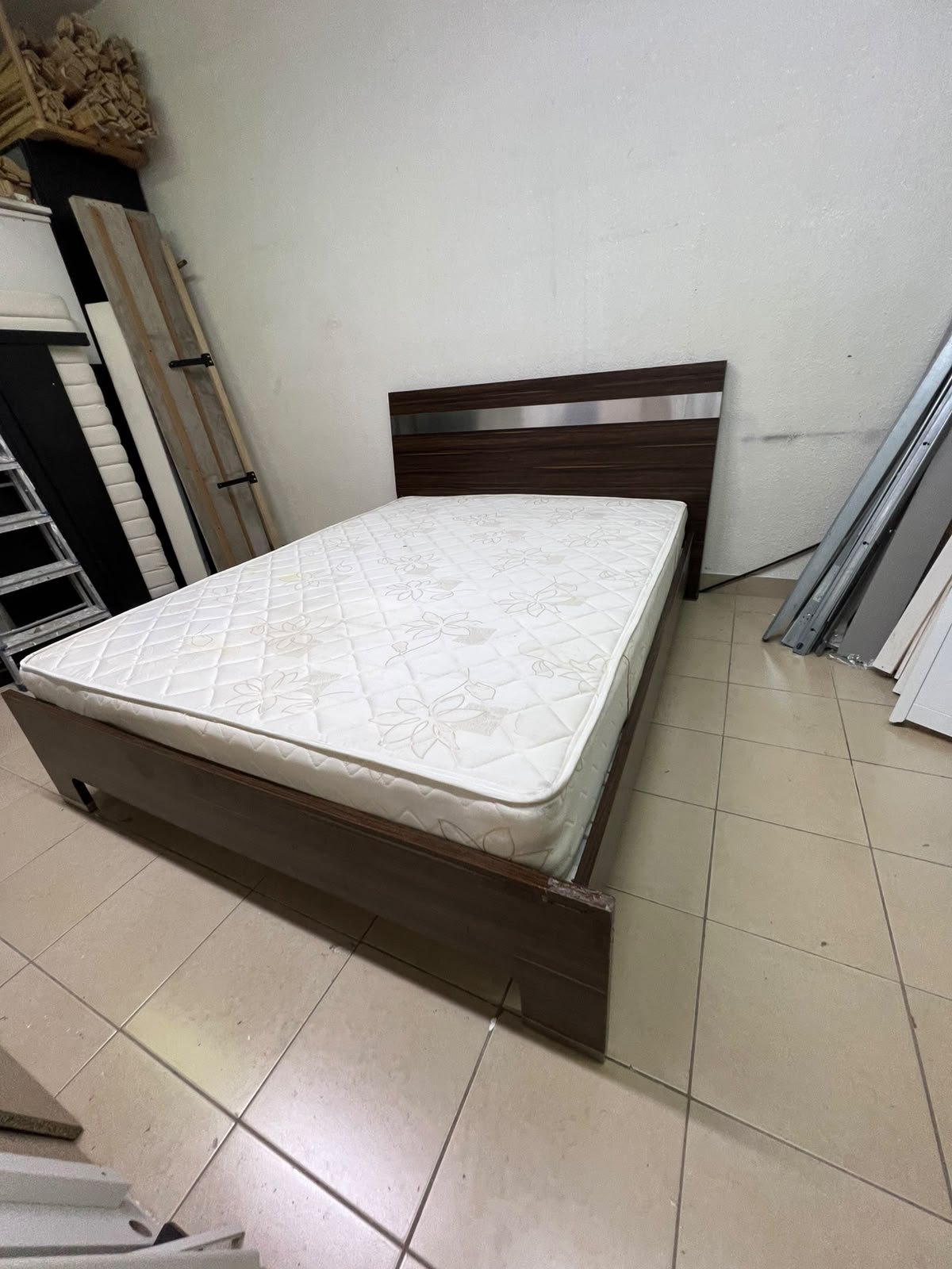 A dark brown wooden double bed featuring a headboard accented with a silver metal strip, and equipped with a white padded mattress. - Image 2